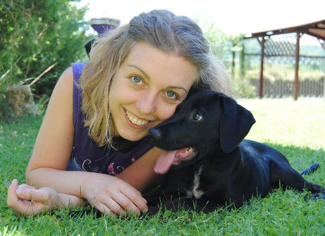 Sara, creatrice di Raggy, sorridente sul prato abbracciata al suo cane nero Newton